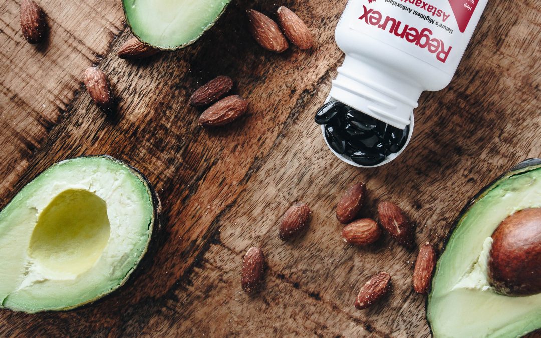 Regenurex bottle with astaxanthin supplements on a wooden table beside avocados and almonds